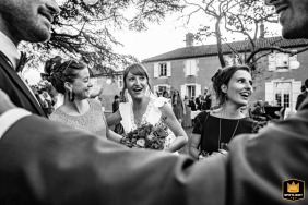 A deep black and white photo of a bride surrounded by friends at Chartreuse de Dane, Gers, France wedding.
